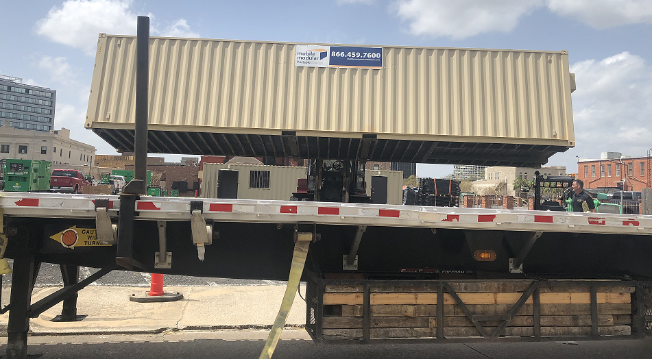 Modular unit being removed from a flatbed via a fork lift